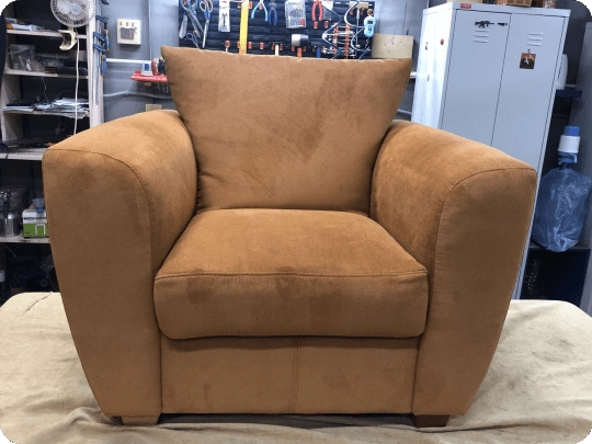 The same armchair recovered in tan suede at the workshop bench