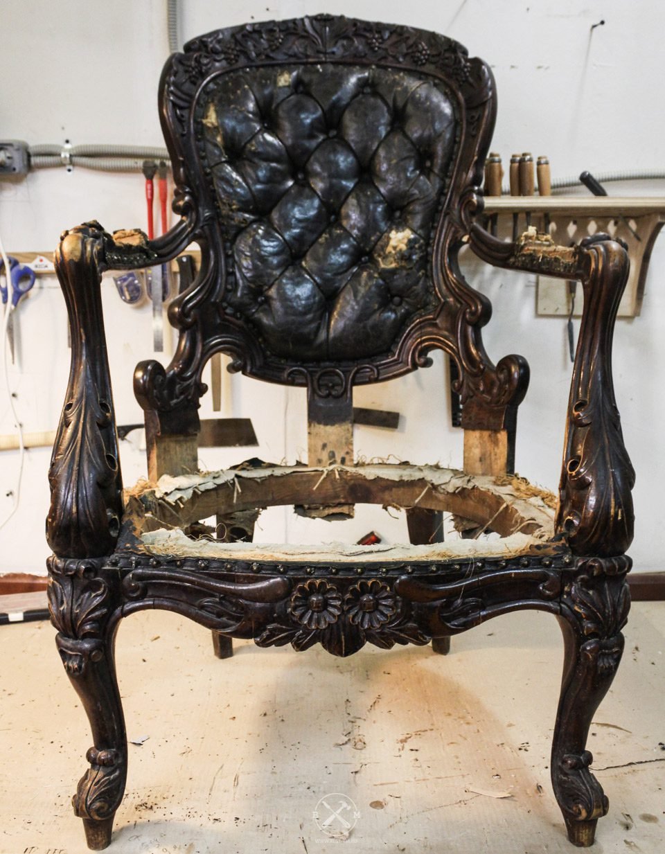 Carved Victorian armchair before restoration, black buttoned leather perished and seat down to the frame