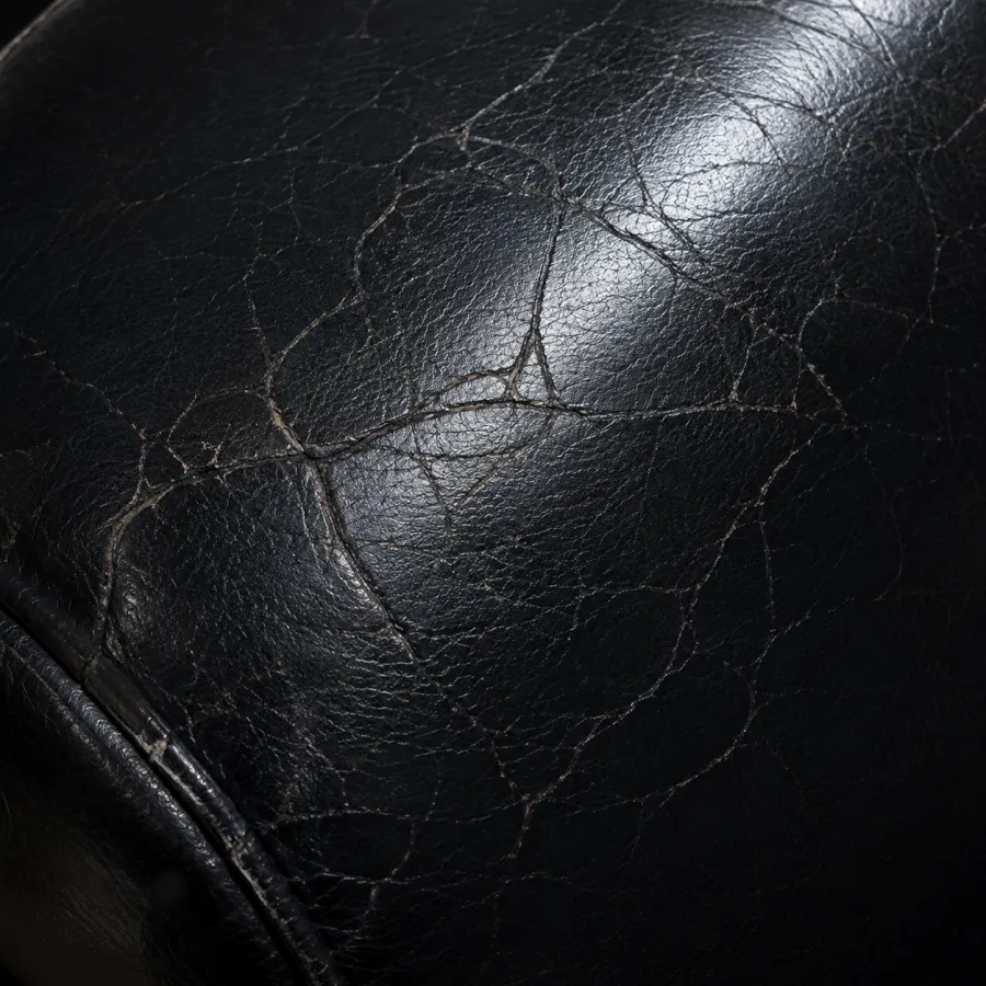 Black bar stool leather broken up by a fine network of surface cracks