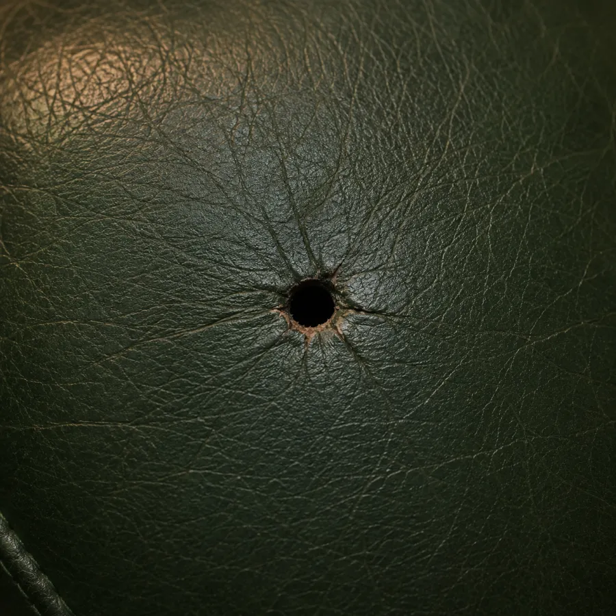 Small puncture in dark leather