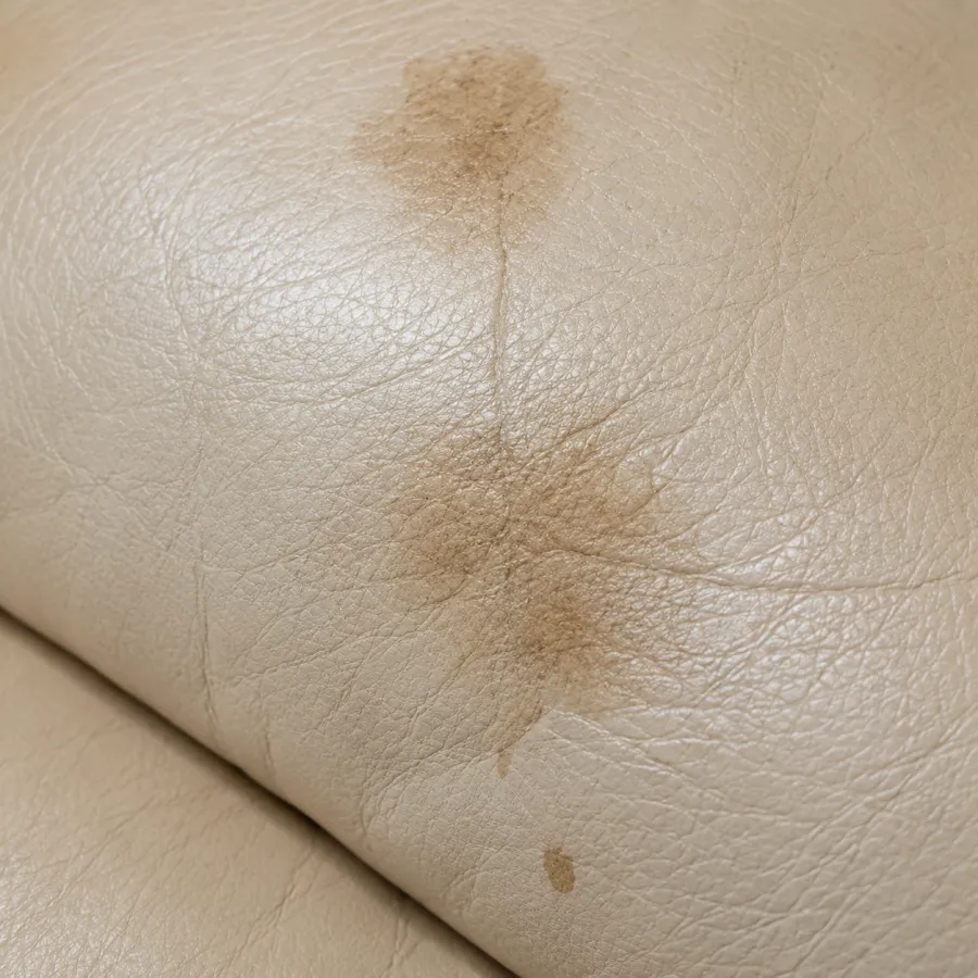 Cream leather marked by a spreading brown stain and a hairline crack
