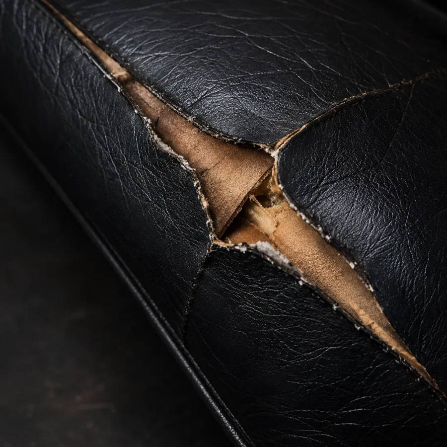 Black leather split open in a long tear with the cut edges curled back