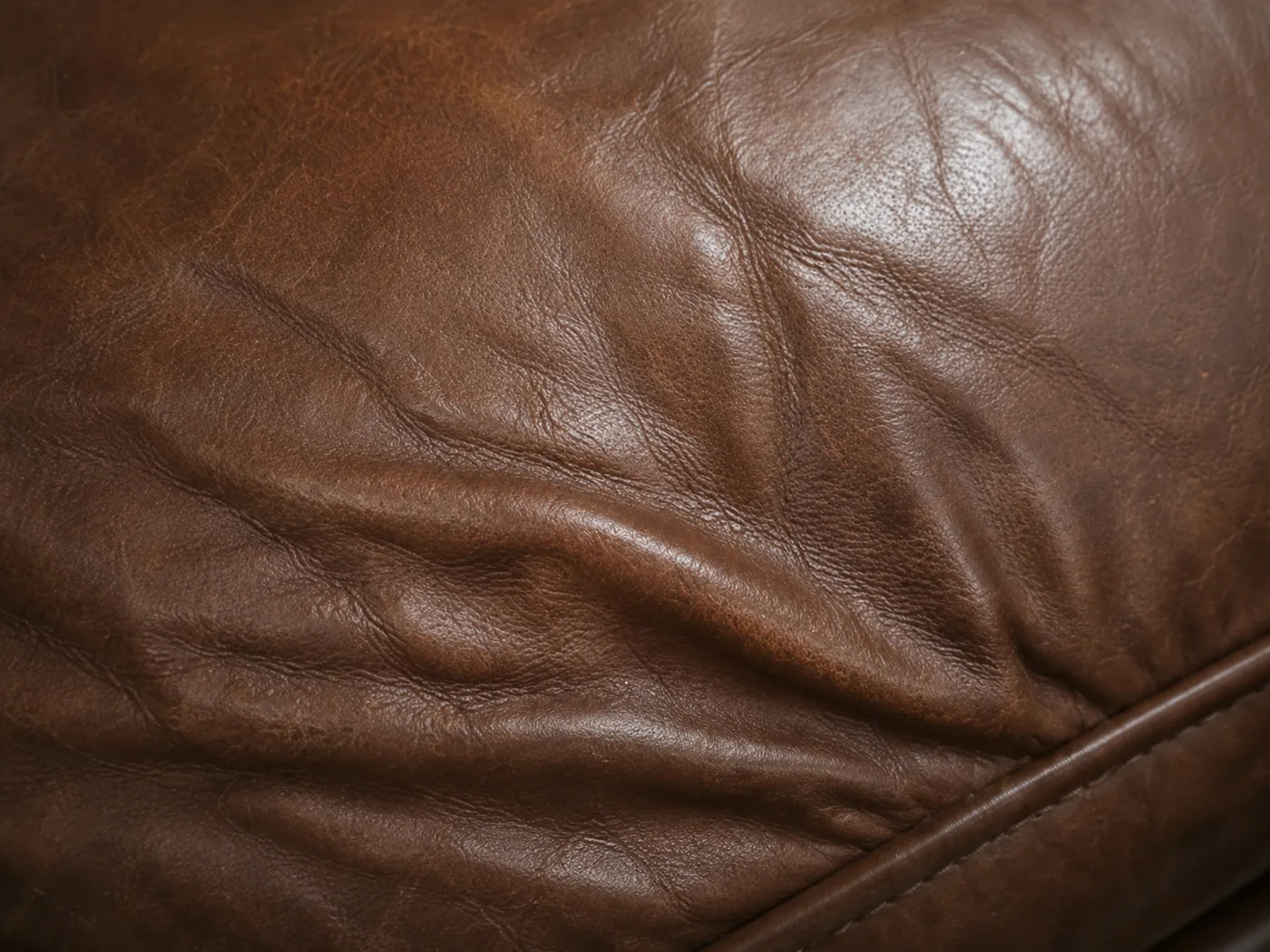 Deep creasing across the front of a brown leather banquette seat