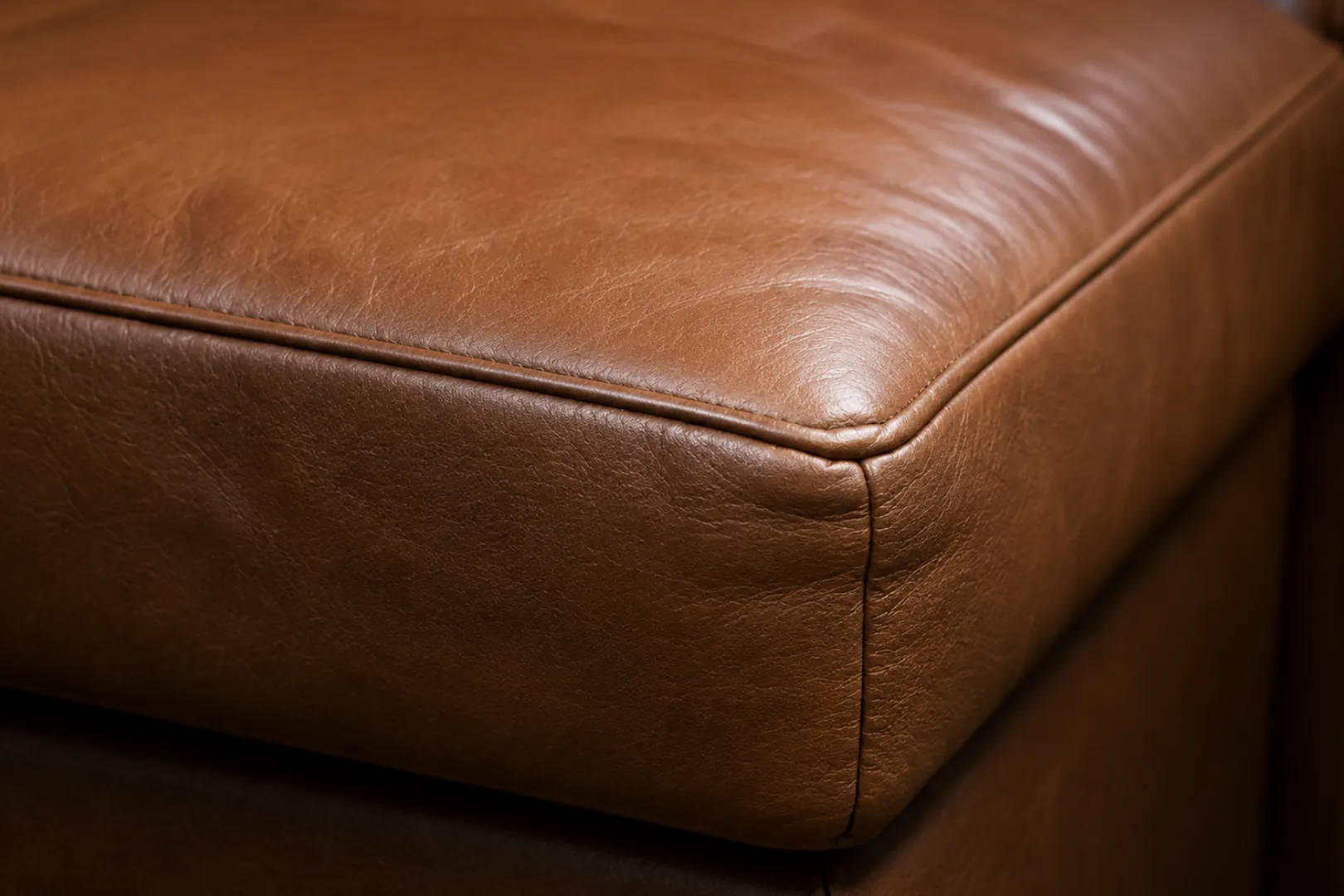 The folded corner of a brown leather cushion