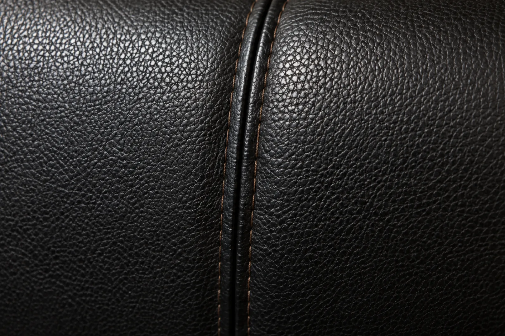 Embossed black leather grain meeting at a stitched seam