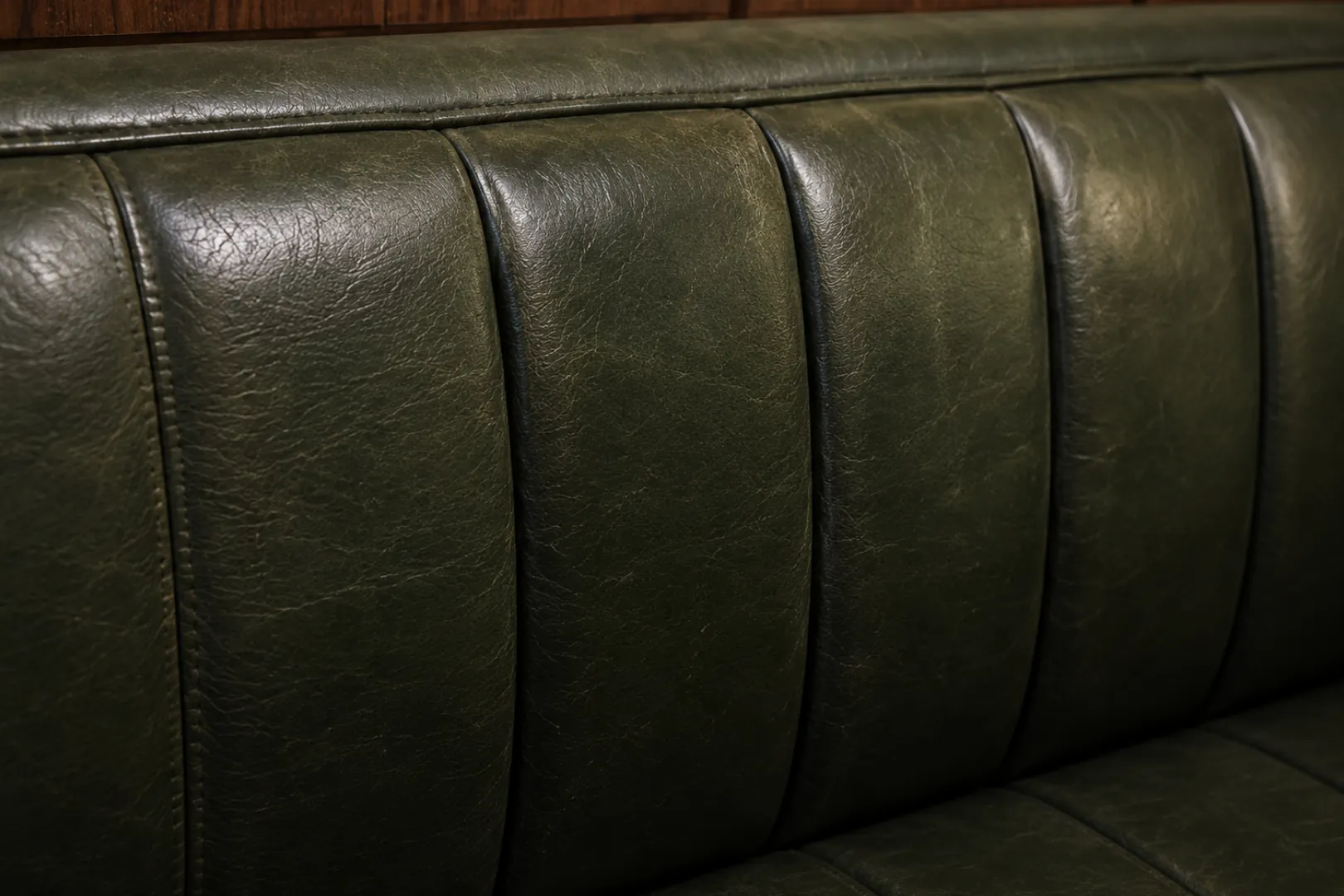 Light catching the sheen on a green channelled leather banquette