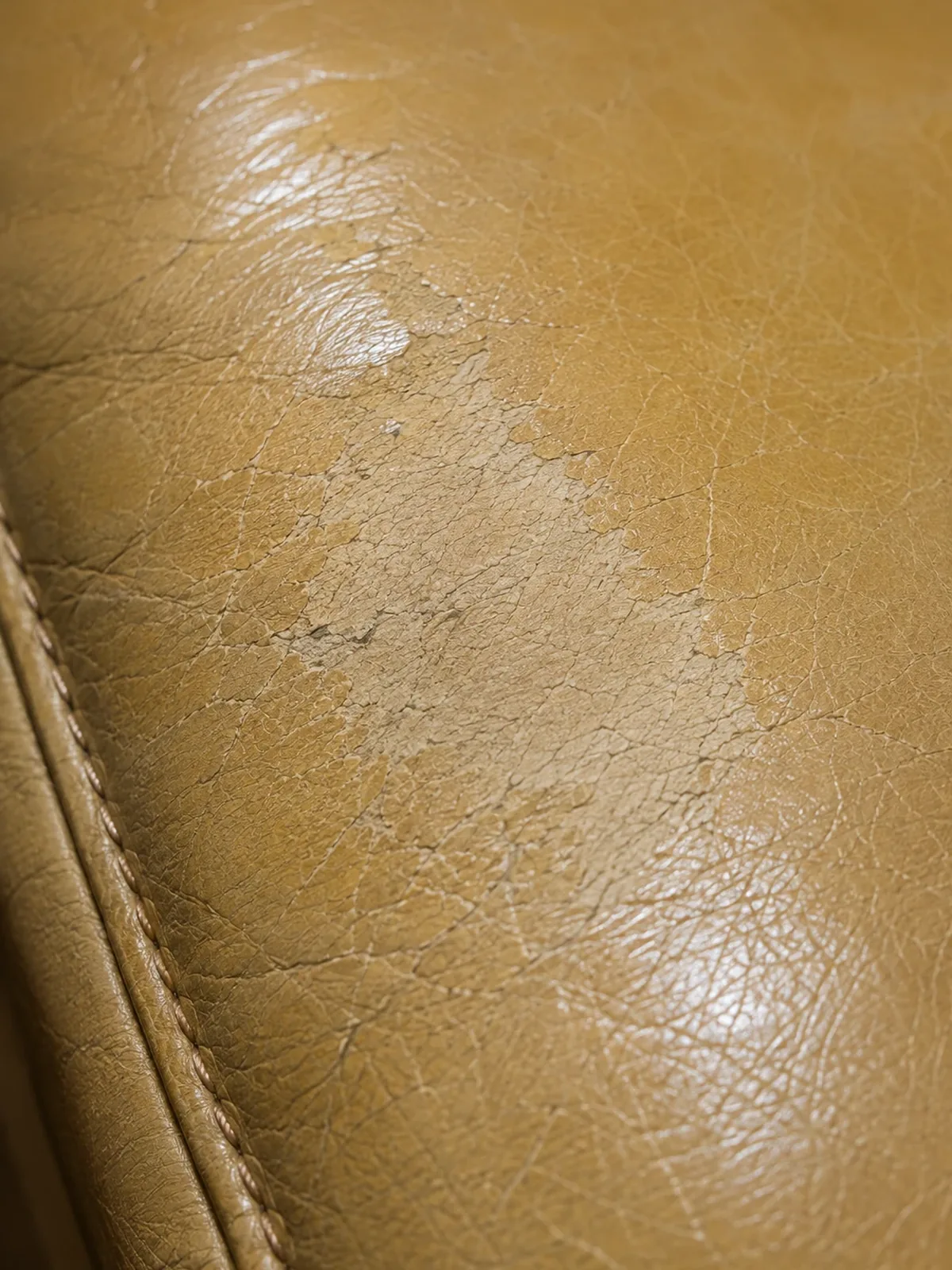 Pale worn patch abraded through the color on a tan hotel leather chair