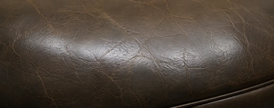 Dark leather cushion with color rubbed off the raised grain