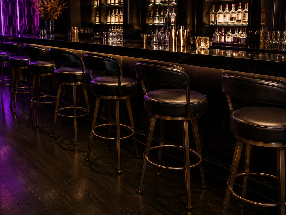 Dark nightclub bar with a row of upholstered stools under low lighting
