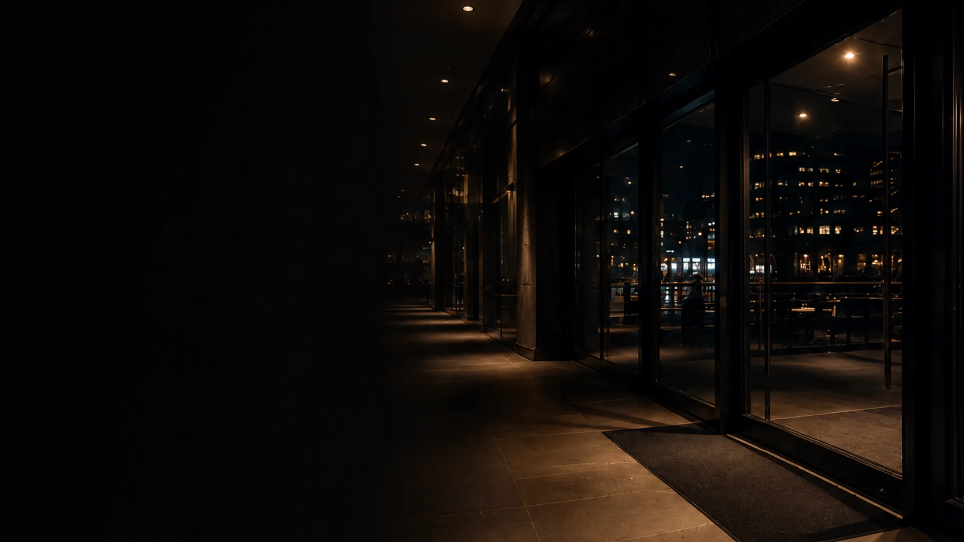 An empty building lobby at night with the city lights beyond the glass