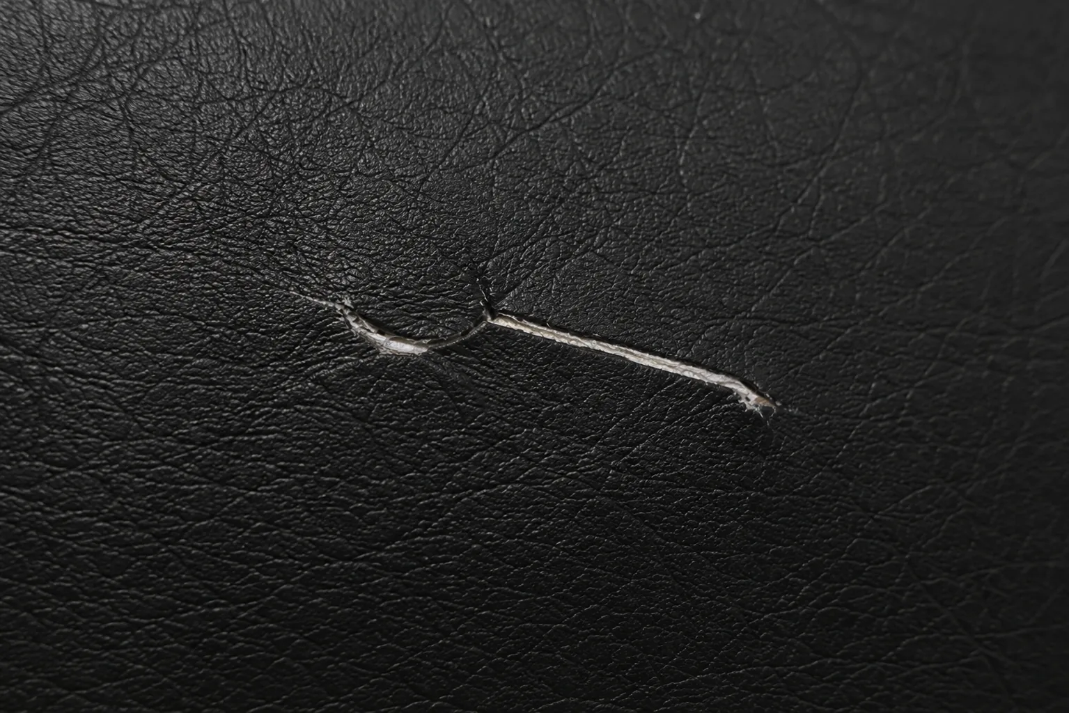 Split tear in black commercial vinyl seating before repair