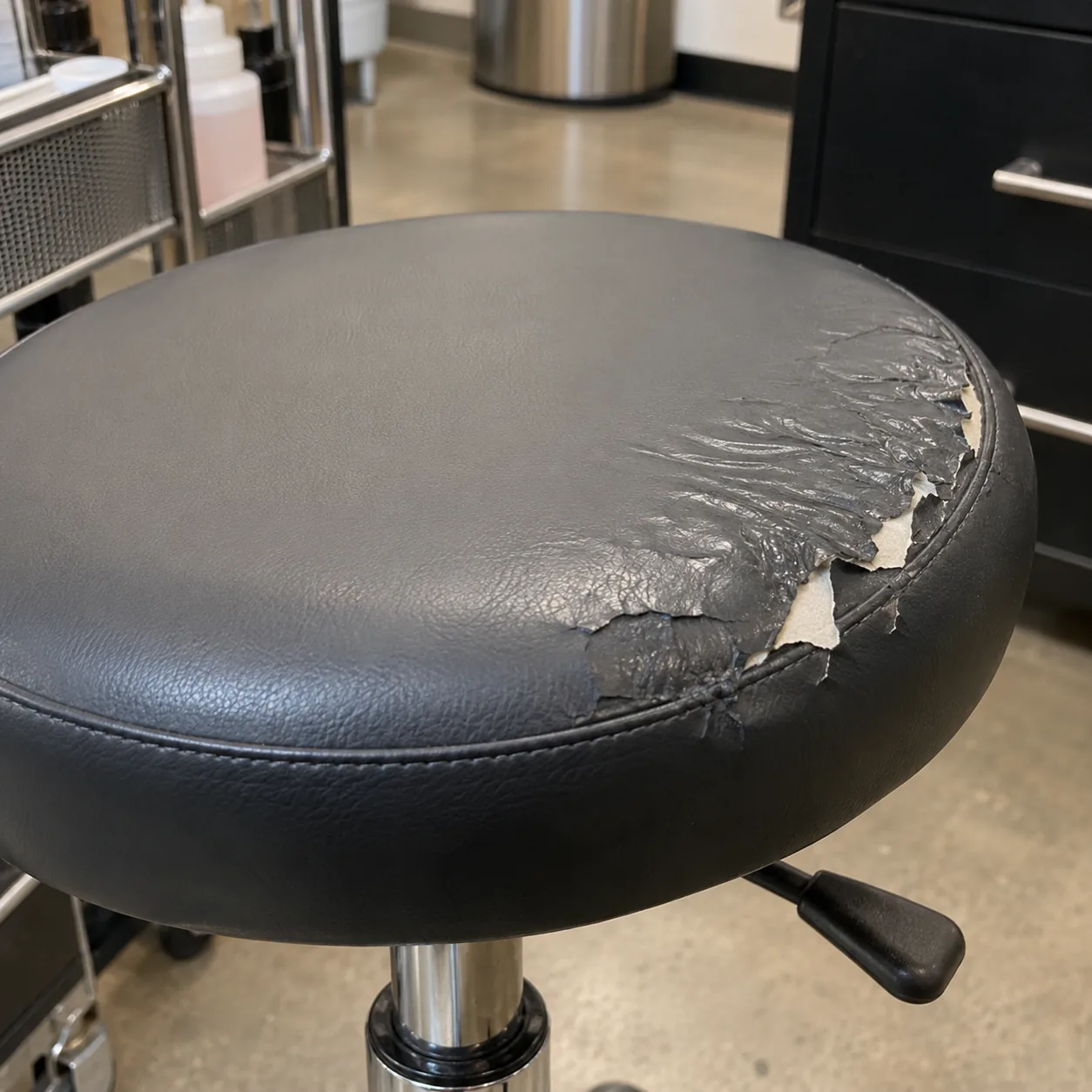 Tacky, peeling vinyl on a manicure stool seat from acetone
