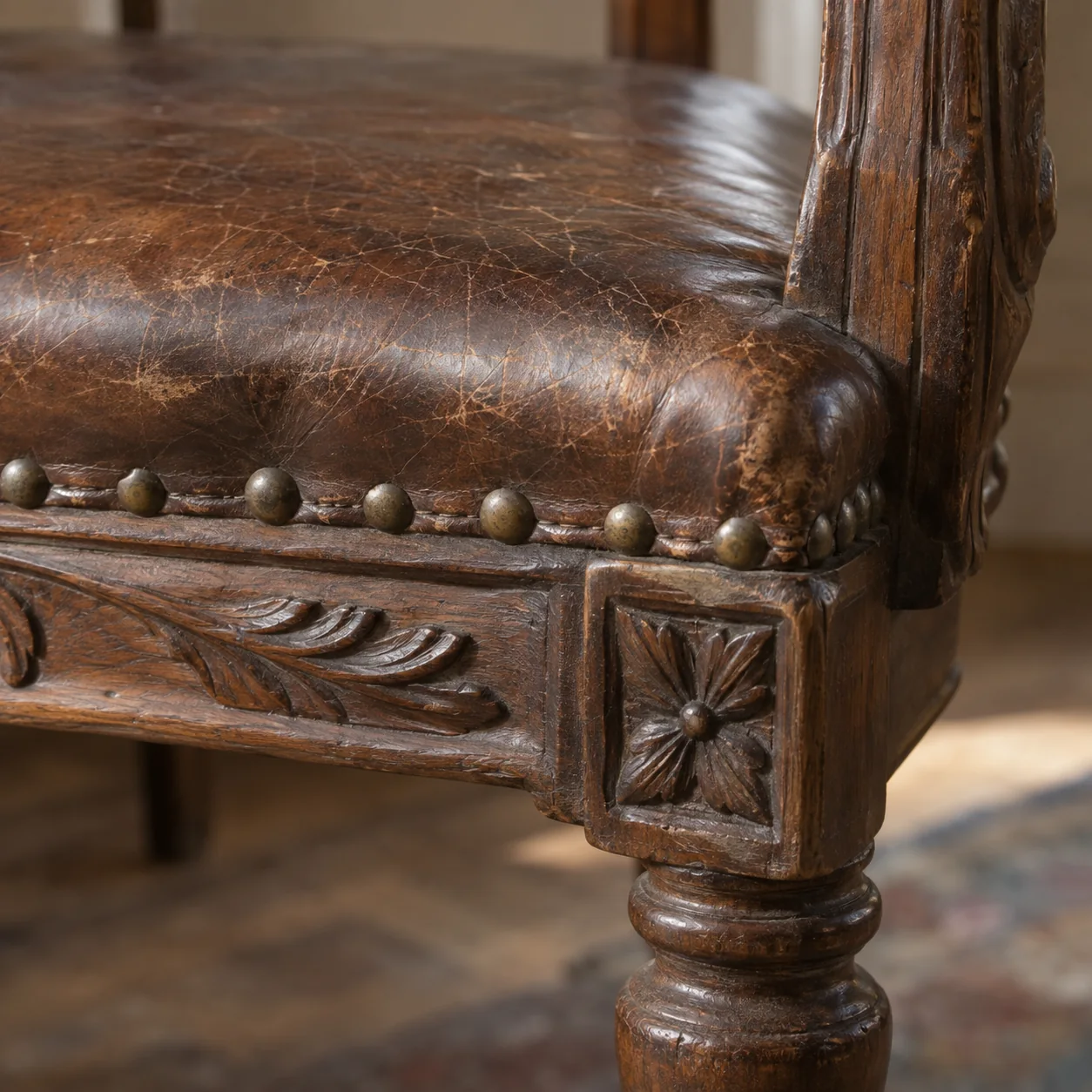 A carved wooden frame meeting the leather seat of an antique chair