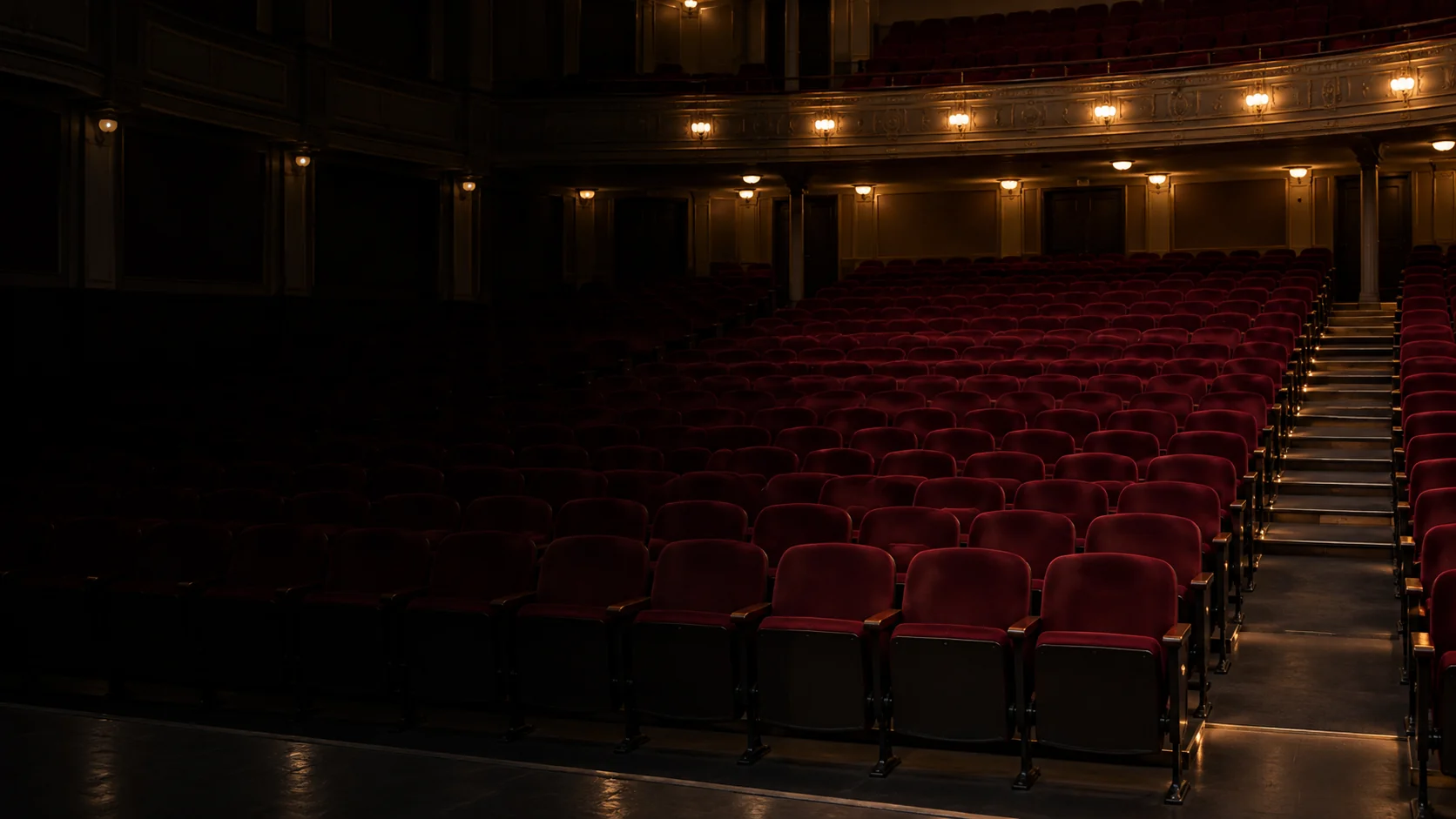 An empty auditorium under work lights, rows waiting for repair