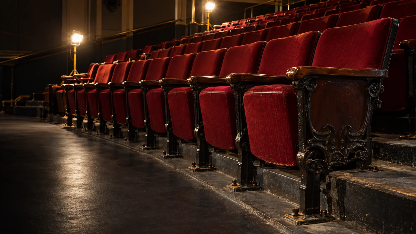 Auditorium seat repair — rows of fixed auditorium seats in an empty house under work lights