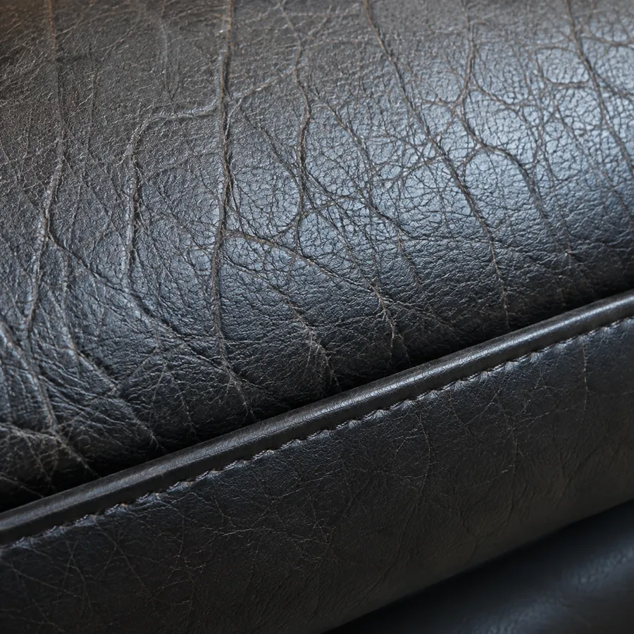 Close view of black leather grain beside a smooth piped edge