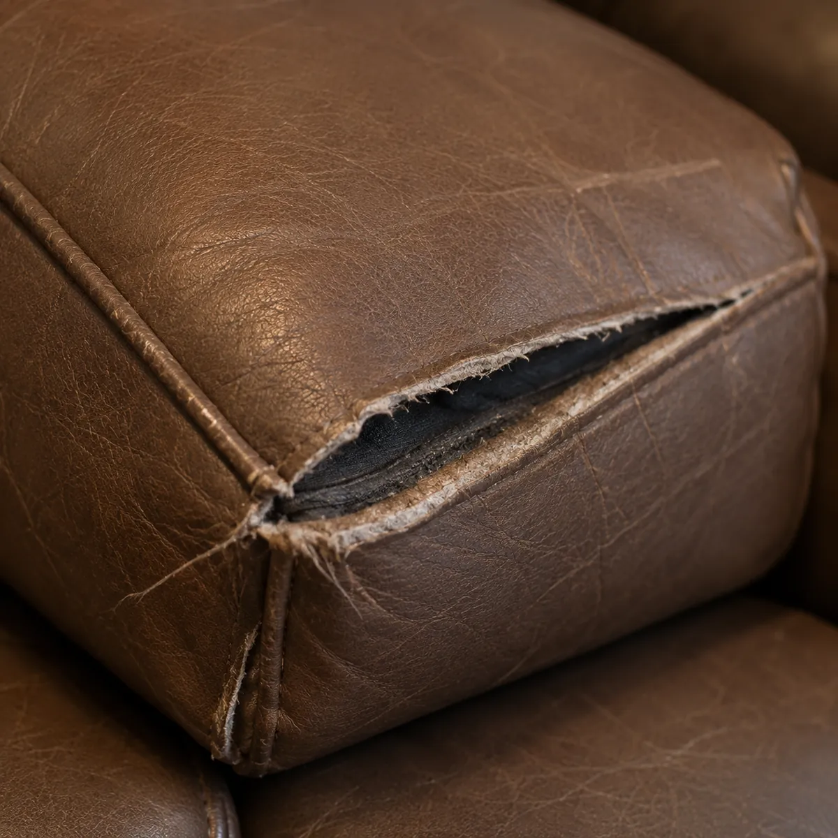 Brown leather cushion with a split seam exposing the lining underneath