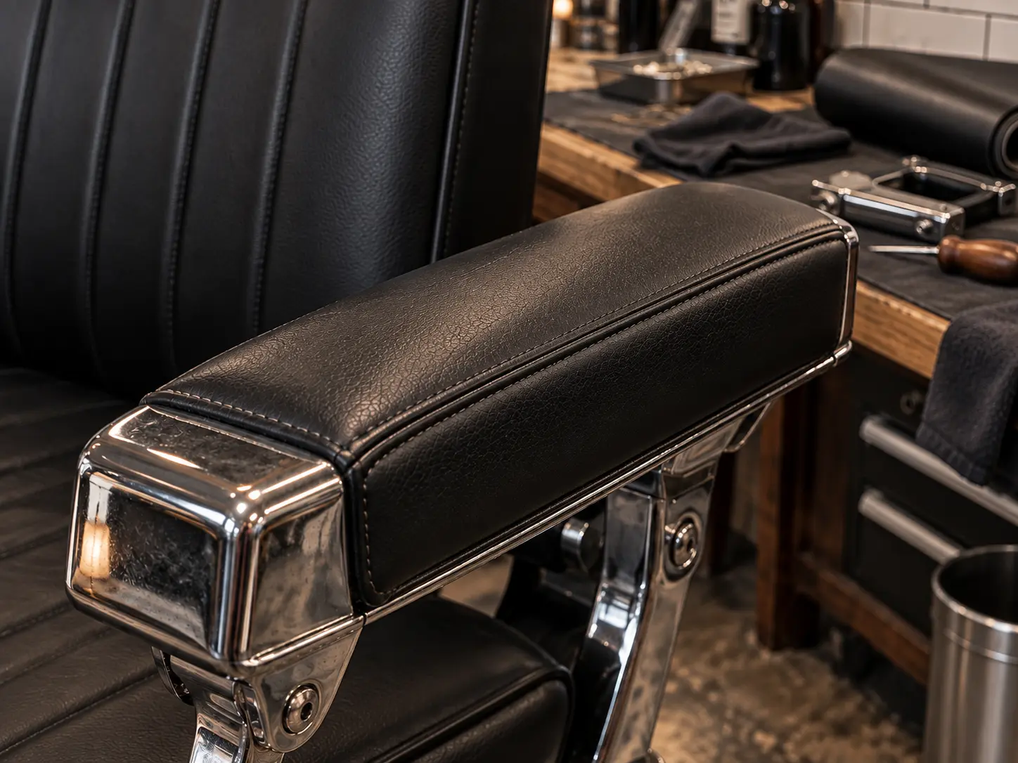 A black barber chair arm pad with a small split repaired