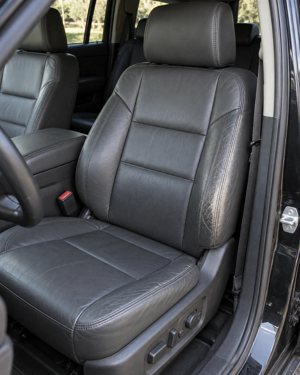 Asiento de auto de cuero gris con el lateral gastado