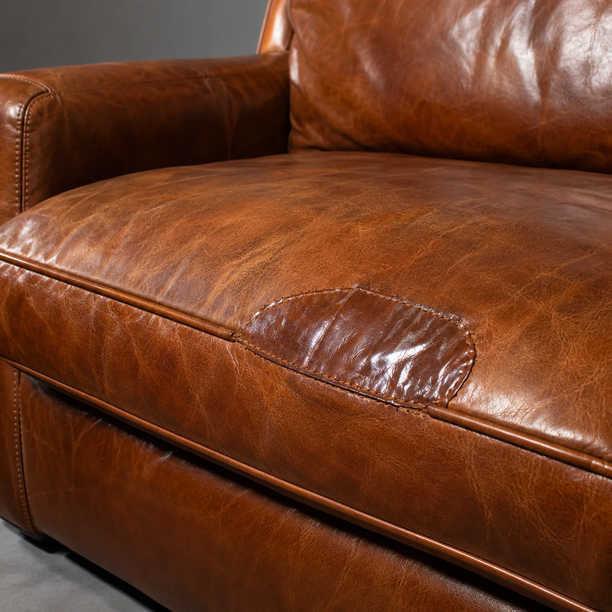Shiny kit patch on a cognac sofa seat, before