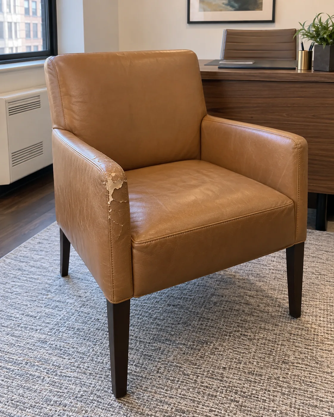 Tan leather guest chair with a peeling arm, before