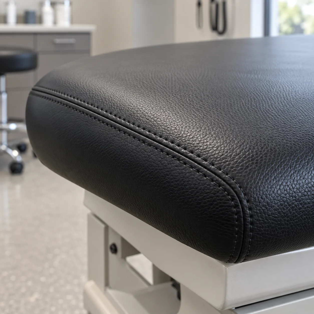 A close view of the stitched edge on a black vinyl exam table pad