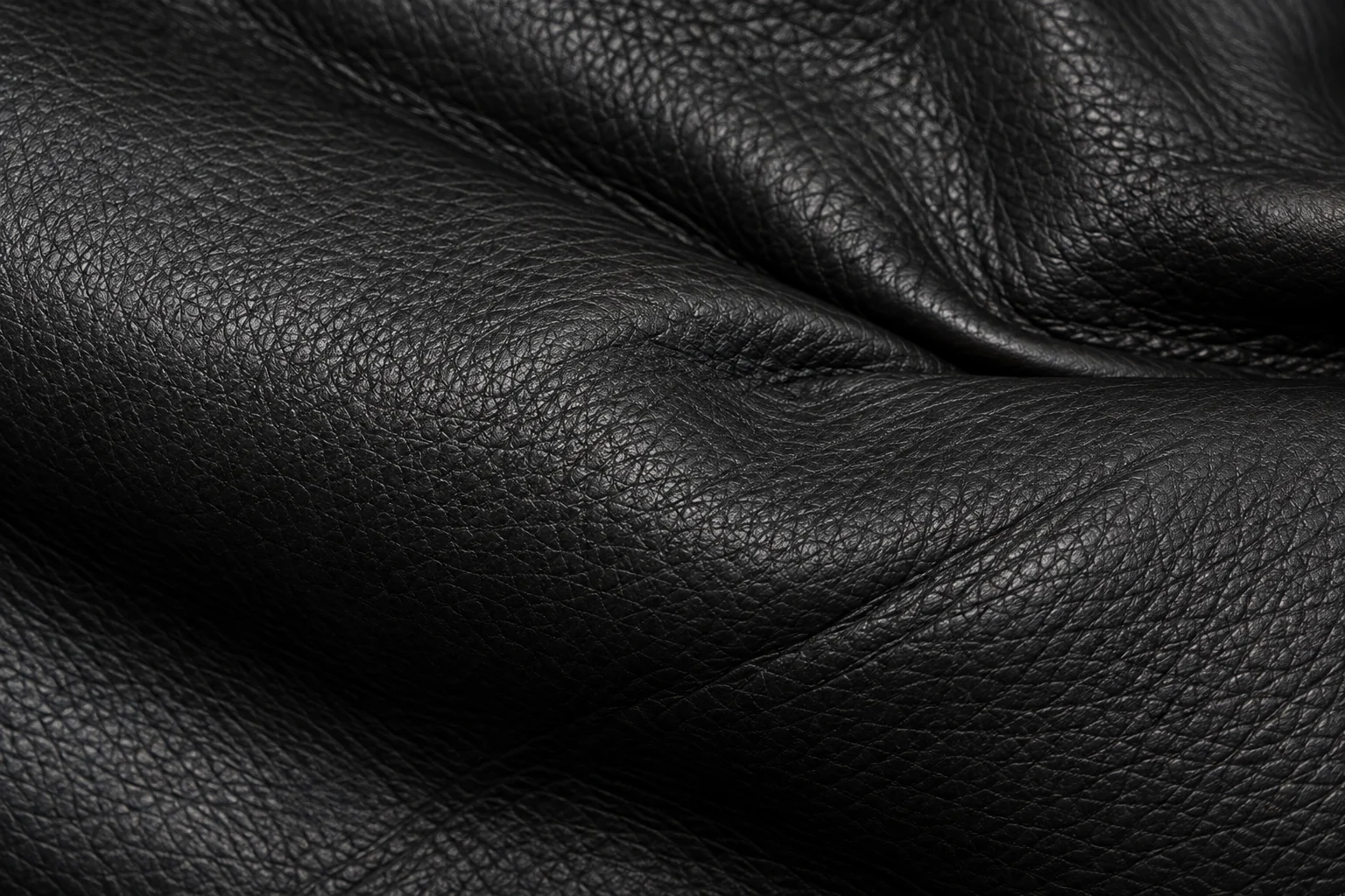 A black hide in draped folds with a pronounced pebble grain