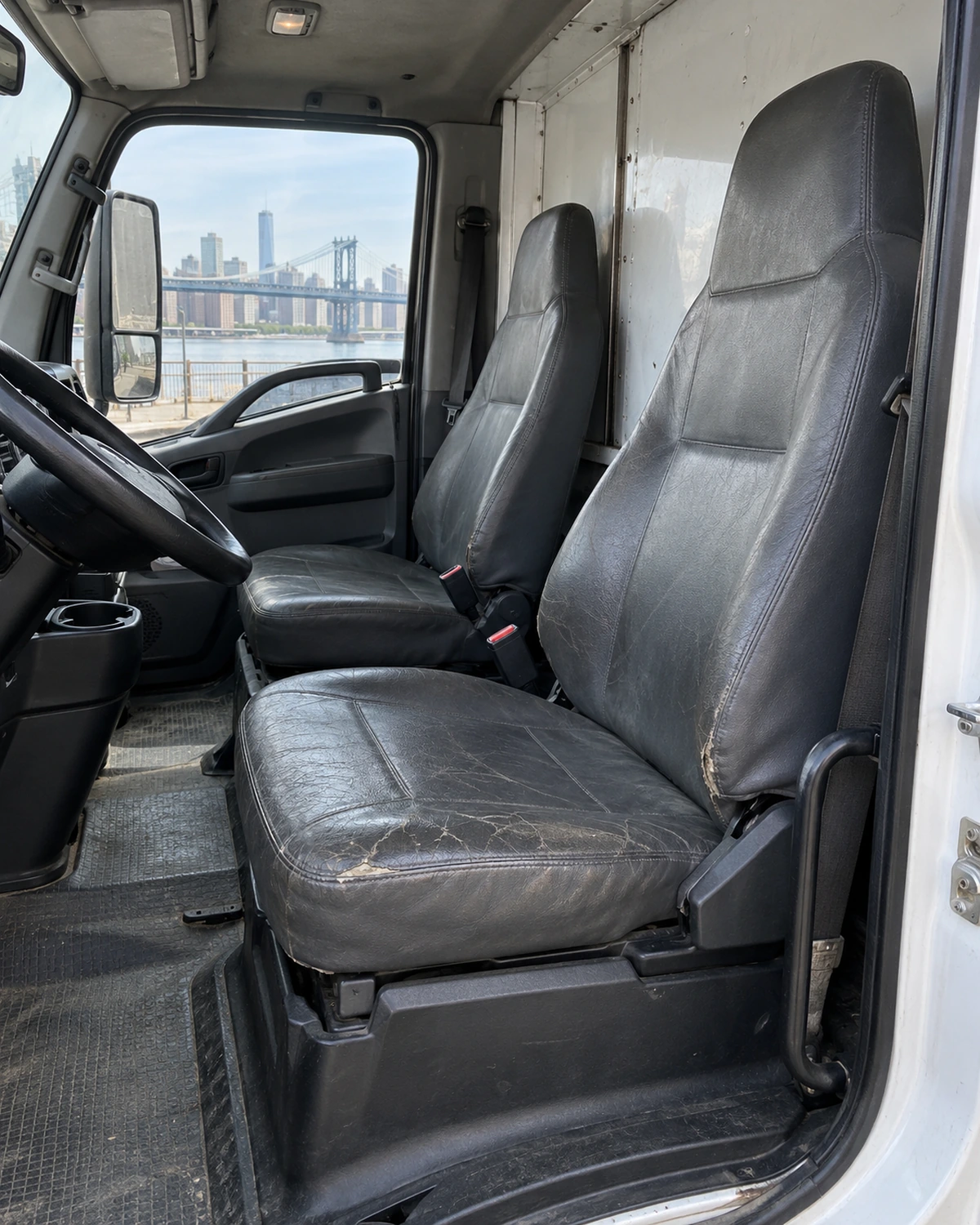 Worn vinyl bench seats in a box truck cab