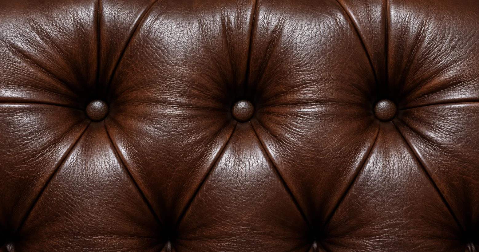 Brown button-tufted leather headboard panel, buttons pulled deep into the padding