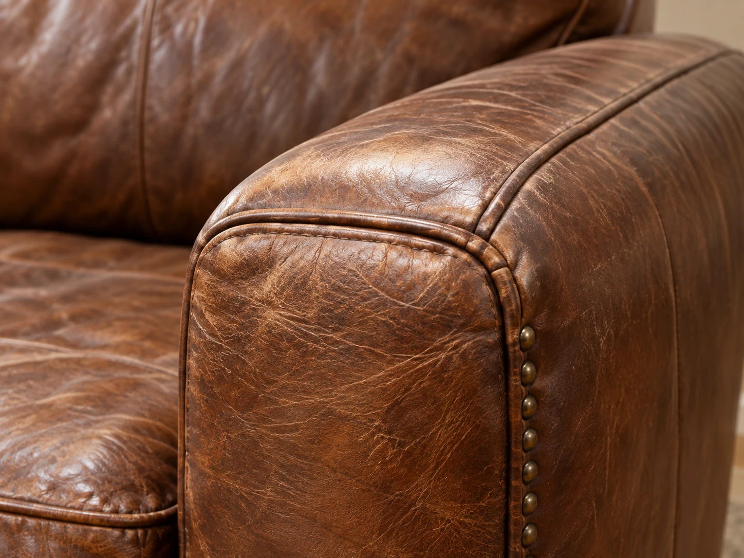 Worn brown leather arm with nailhead trim