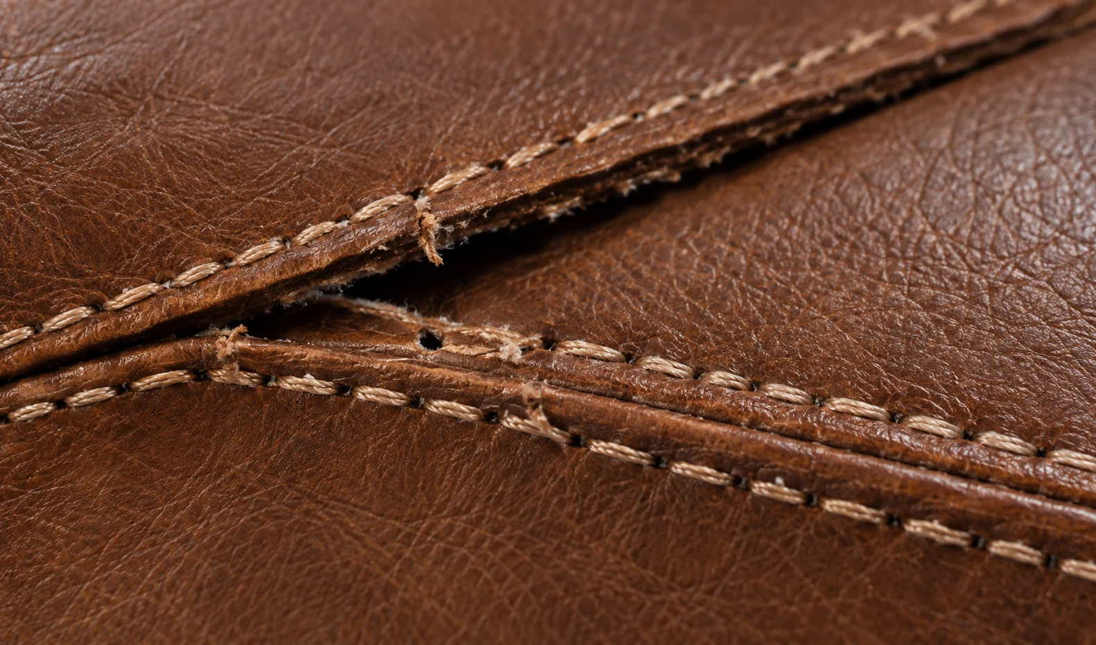 Two parallel rows of stitching running across a brown leather bed panel