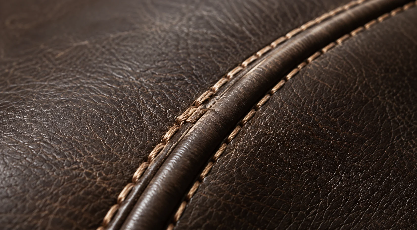 Sound piped edge on a brown leather bed with even contrast stitching running along it