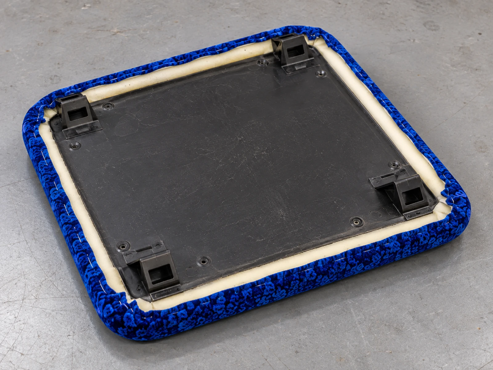 A bus seat insert pad face down on a bench, showing cover, foam and board