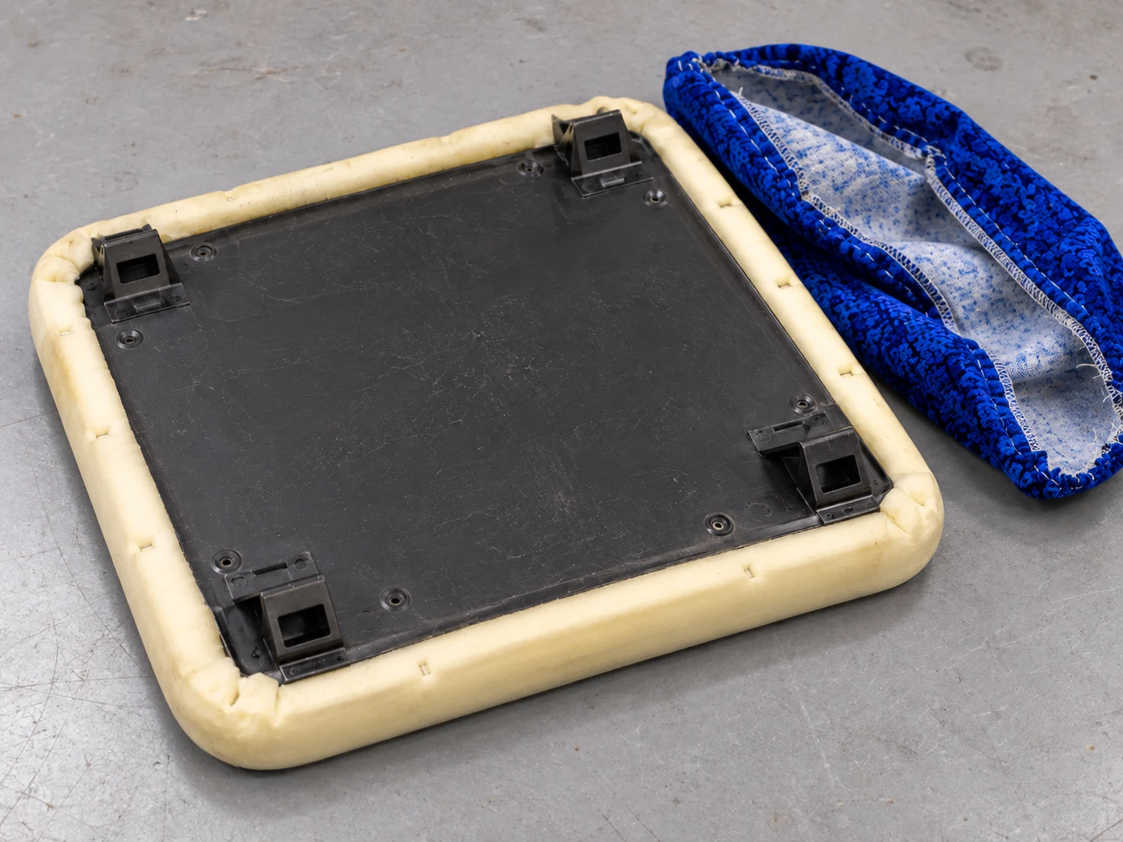 A bus seat insert stripped, with the old cover folded beside the bare board