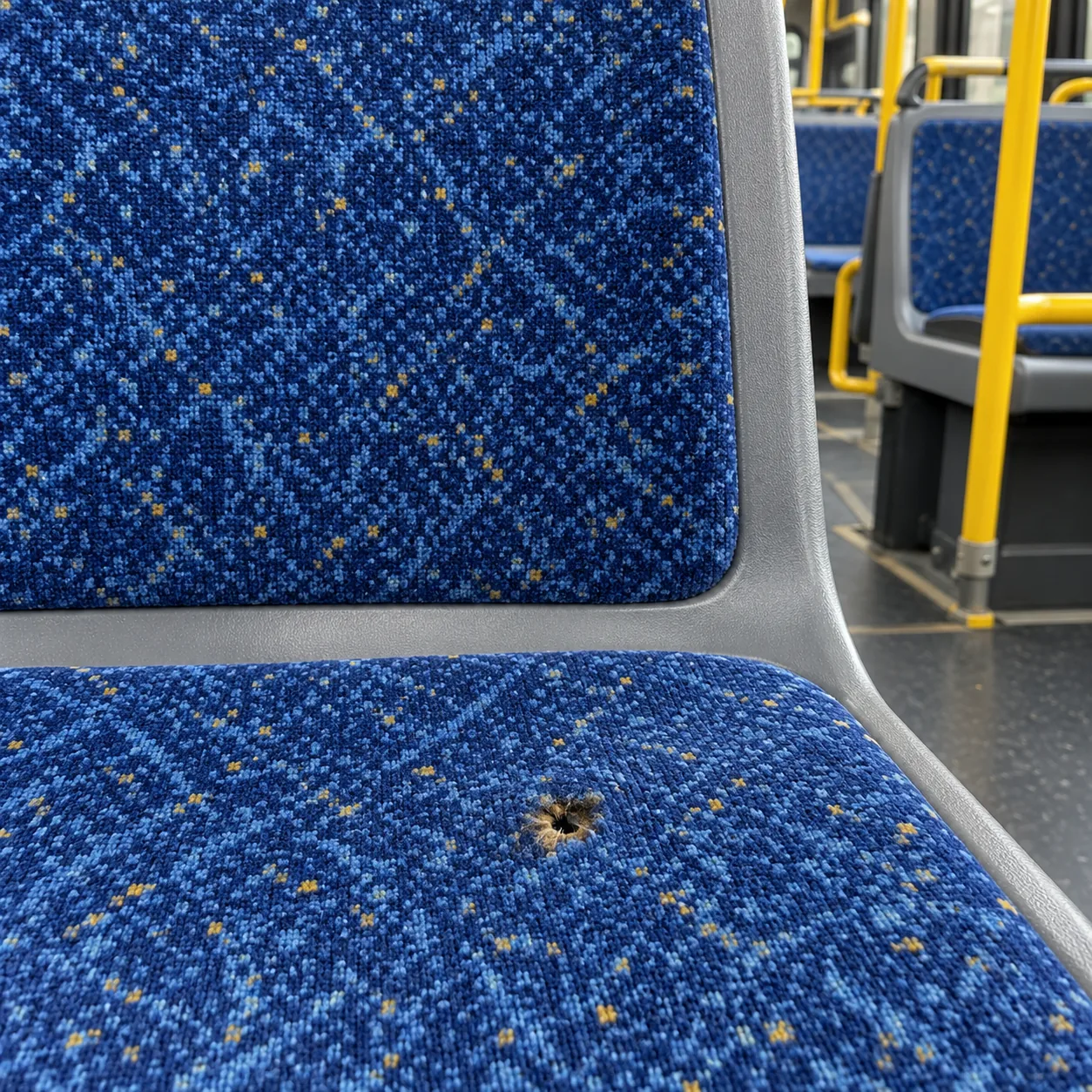 A cigarette burn hole in a bus seat cover