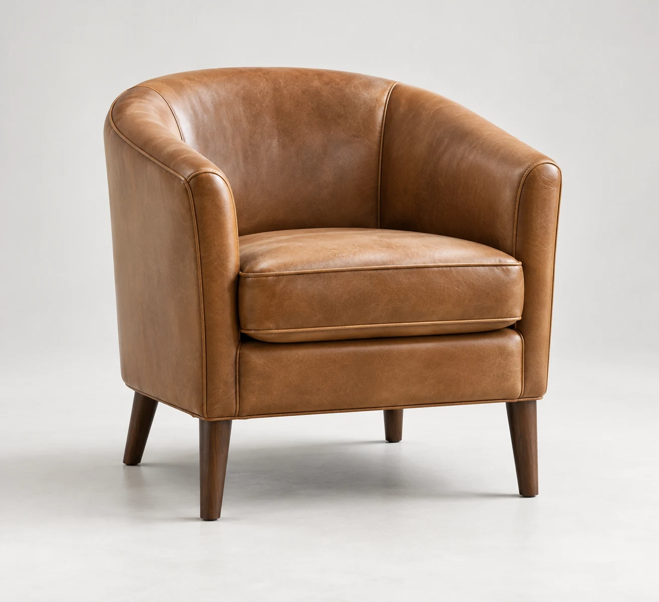 Cognac leather club chair with a curved back and wood legs