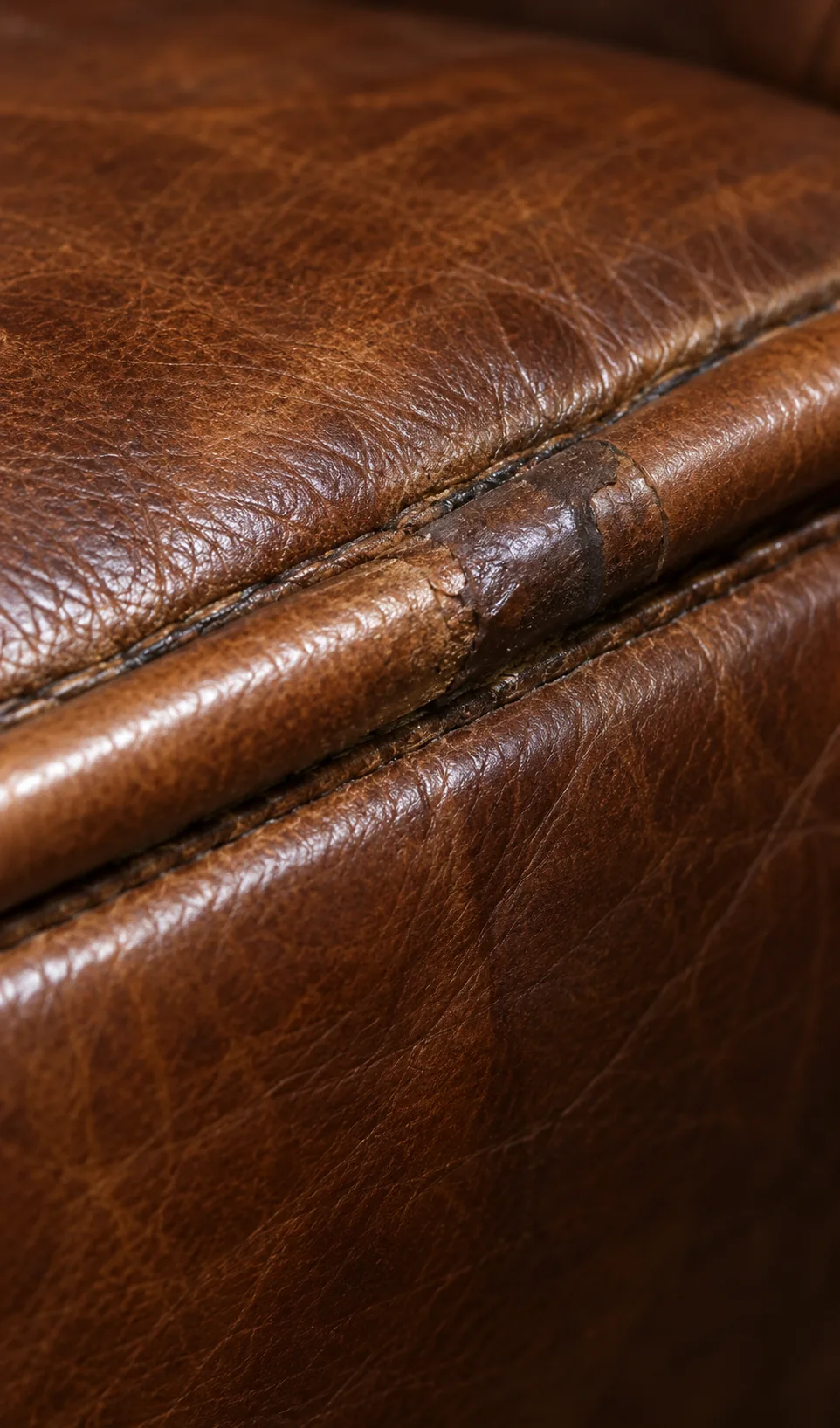 Close-up of a failed earlier seam repair on cognac leather