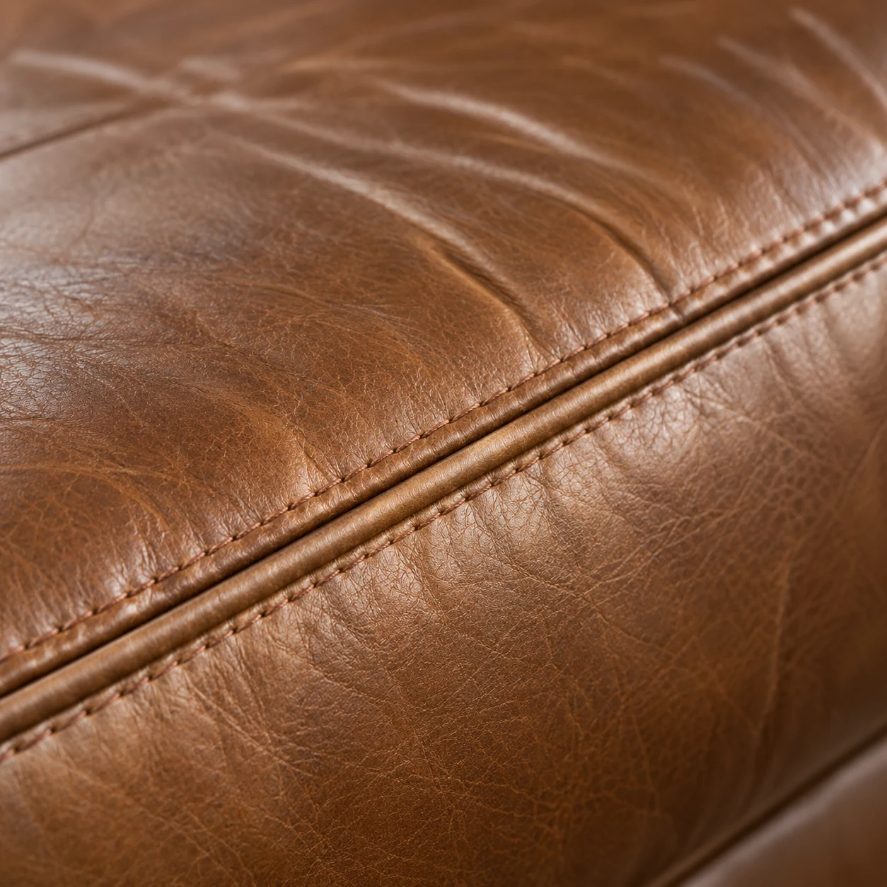 Welt seam along a cognac sectional cushion