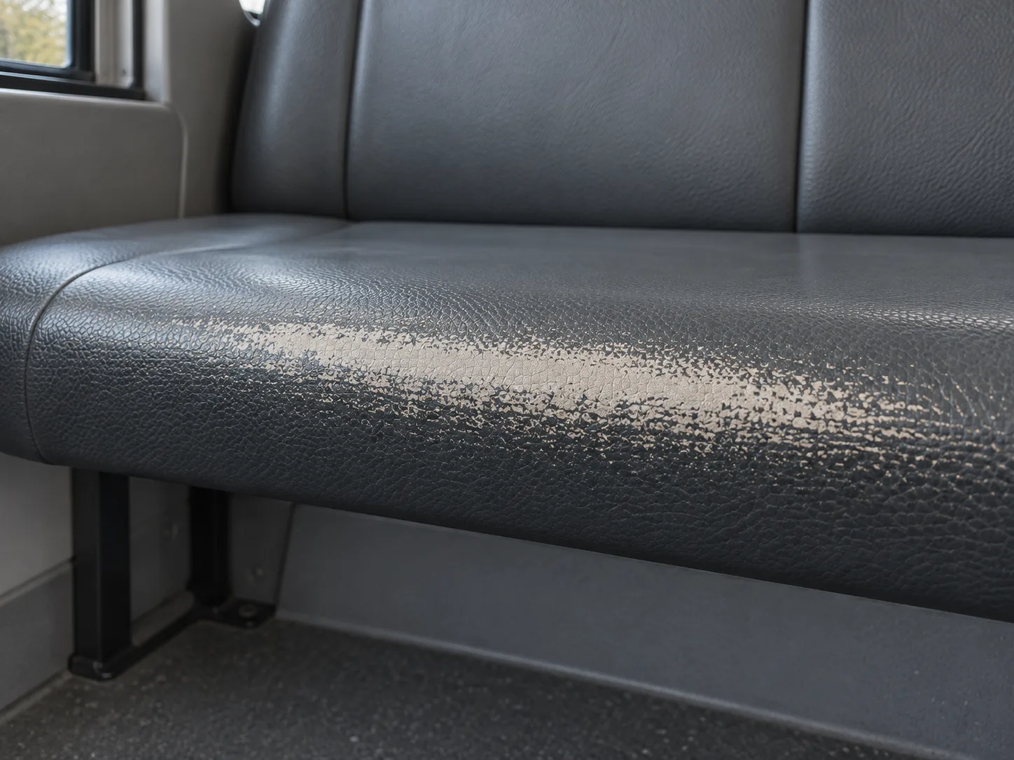 The front edge of a vinyl seat with the color worn off