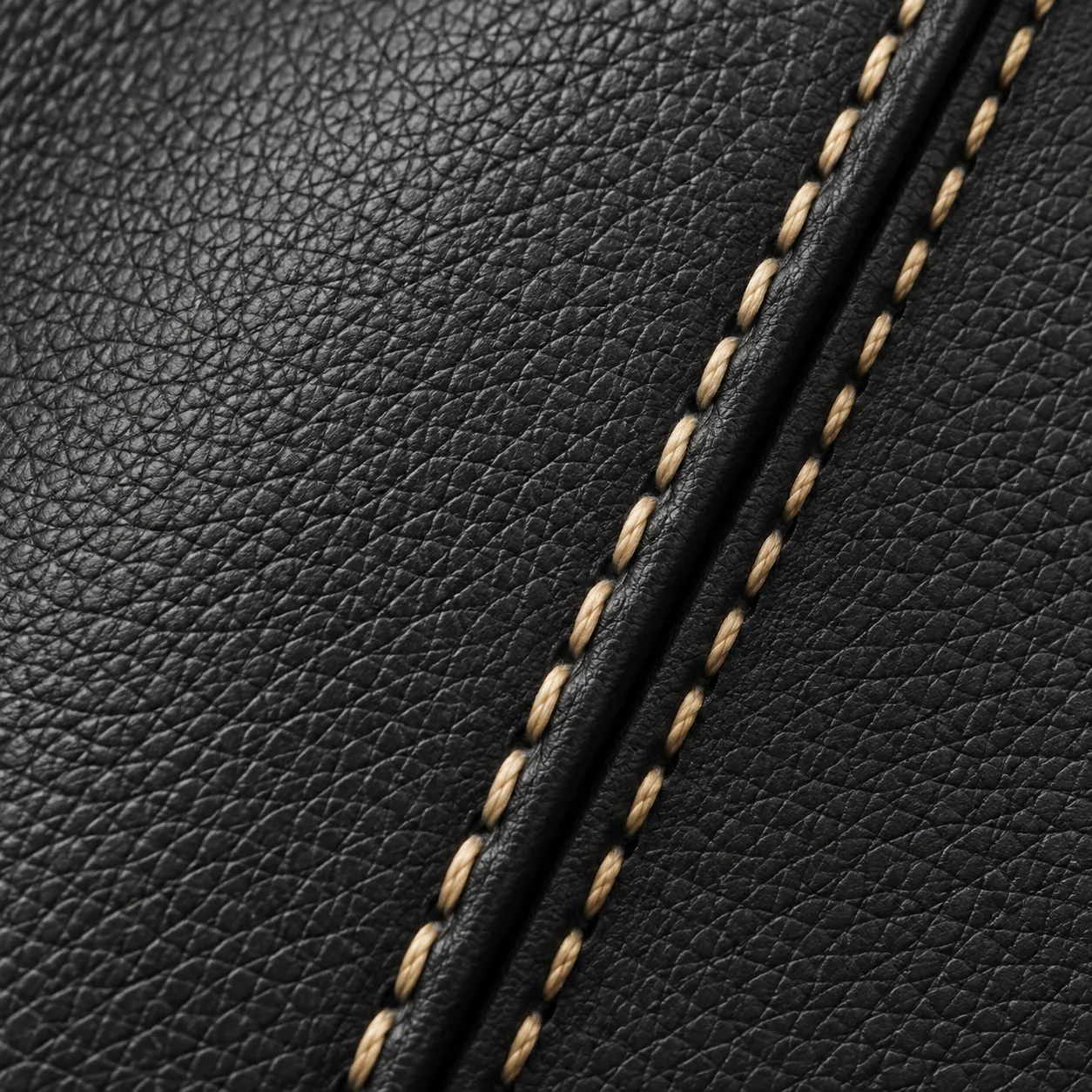Contrast tan saddle stitch running along a welted seam in black leather