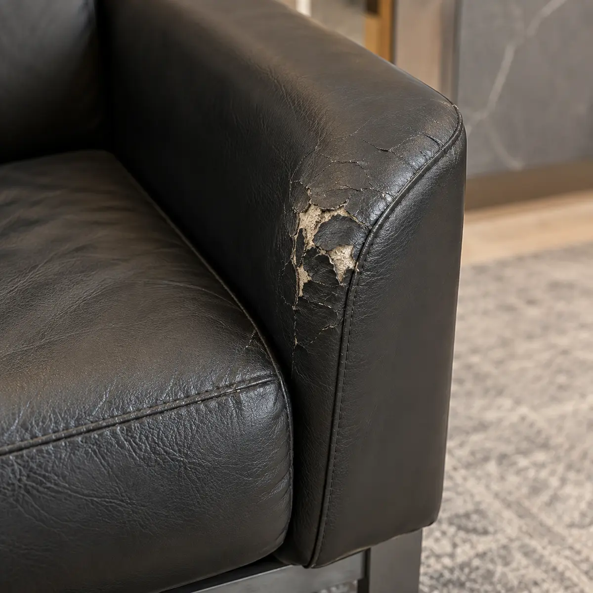 Cracked, peeling leather on the arm of a black lobby chair