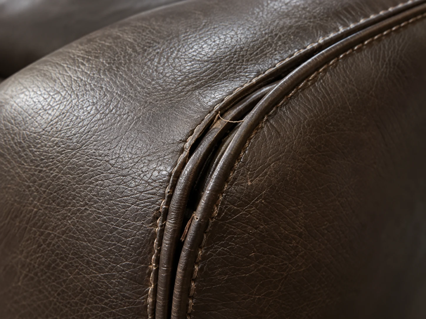 Double-stitched seam running across dark brown leather, both rows of thread intact