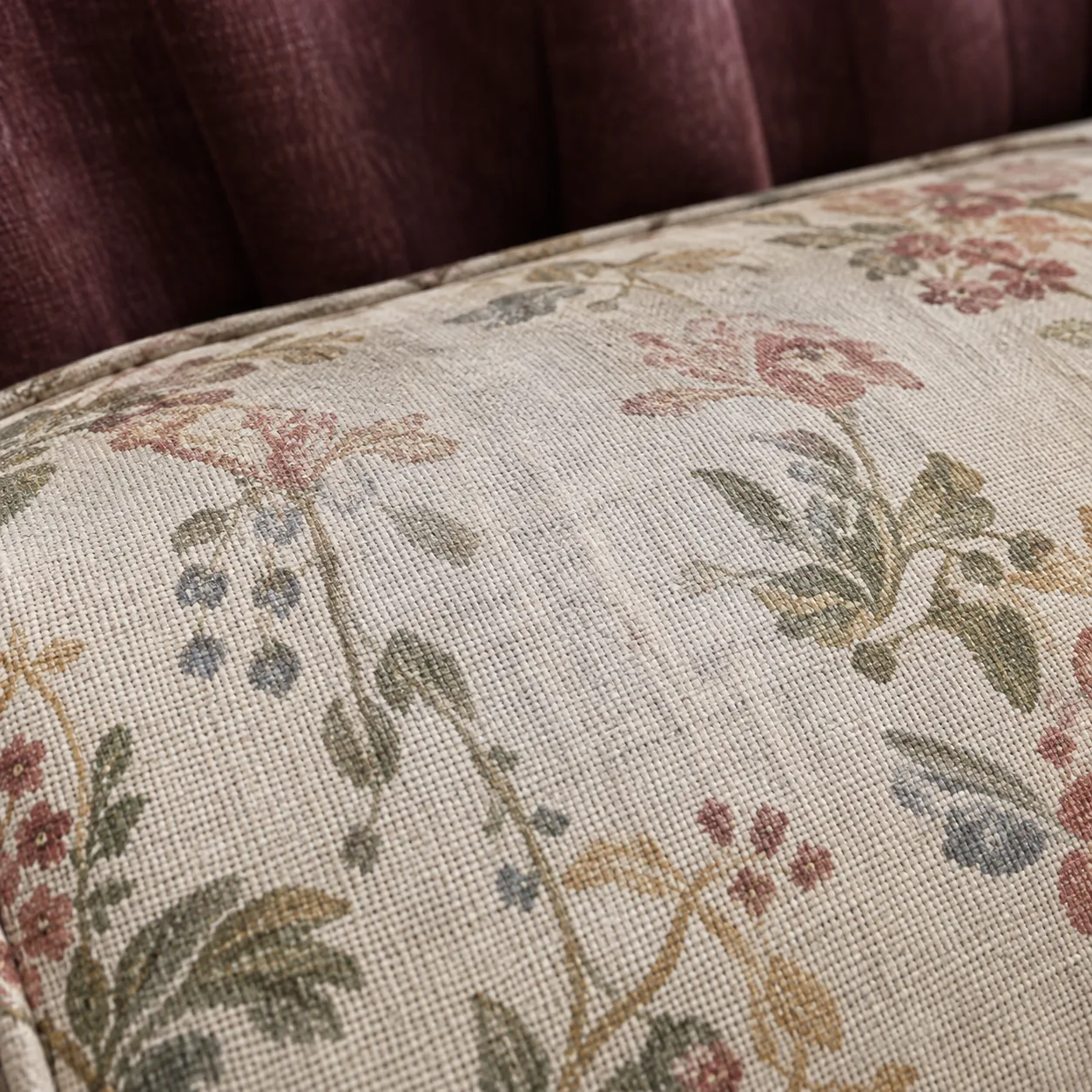 Floral chintz on a headboard roll edge above a burgundy channelled back