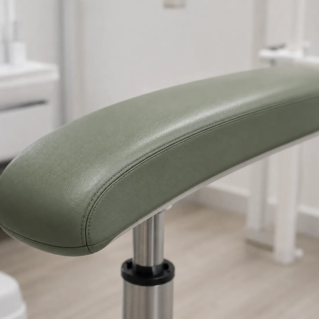 Sage green vinyl dental chair armrest pad on its bracket