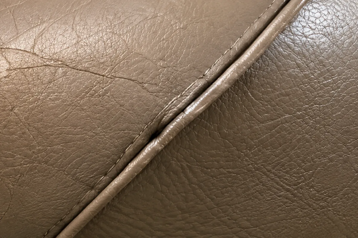 Close-up of cracked vinyl beside a stitched seam on a dental chair