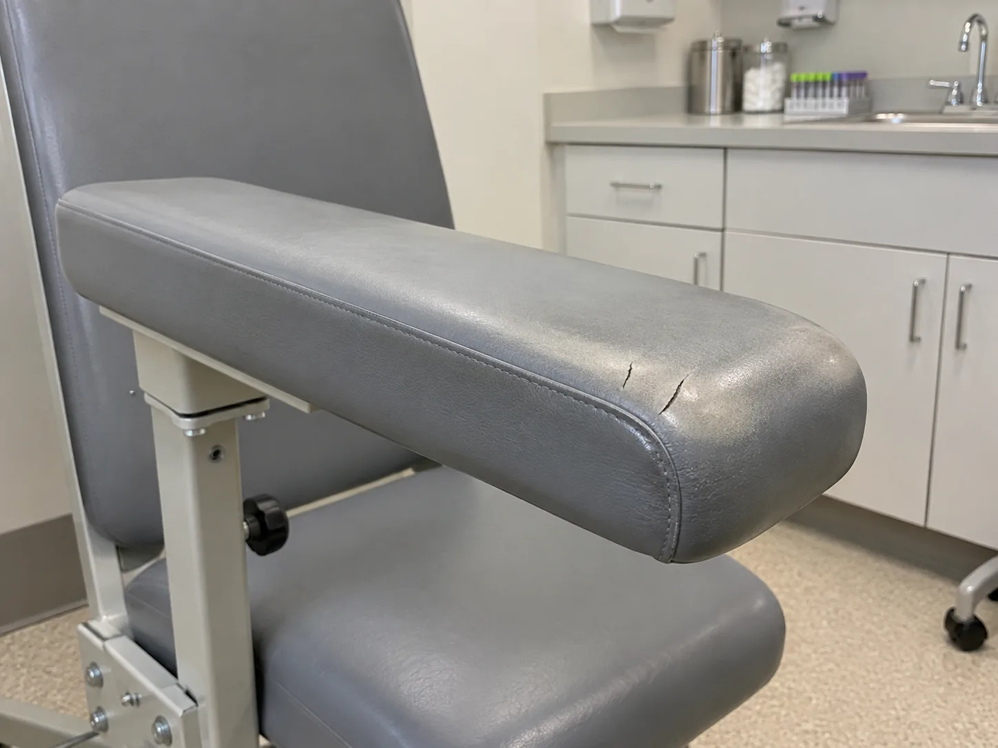 A grey vinyl draw-chair arm cracked at the front before recovery