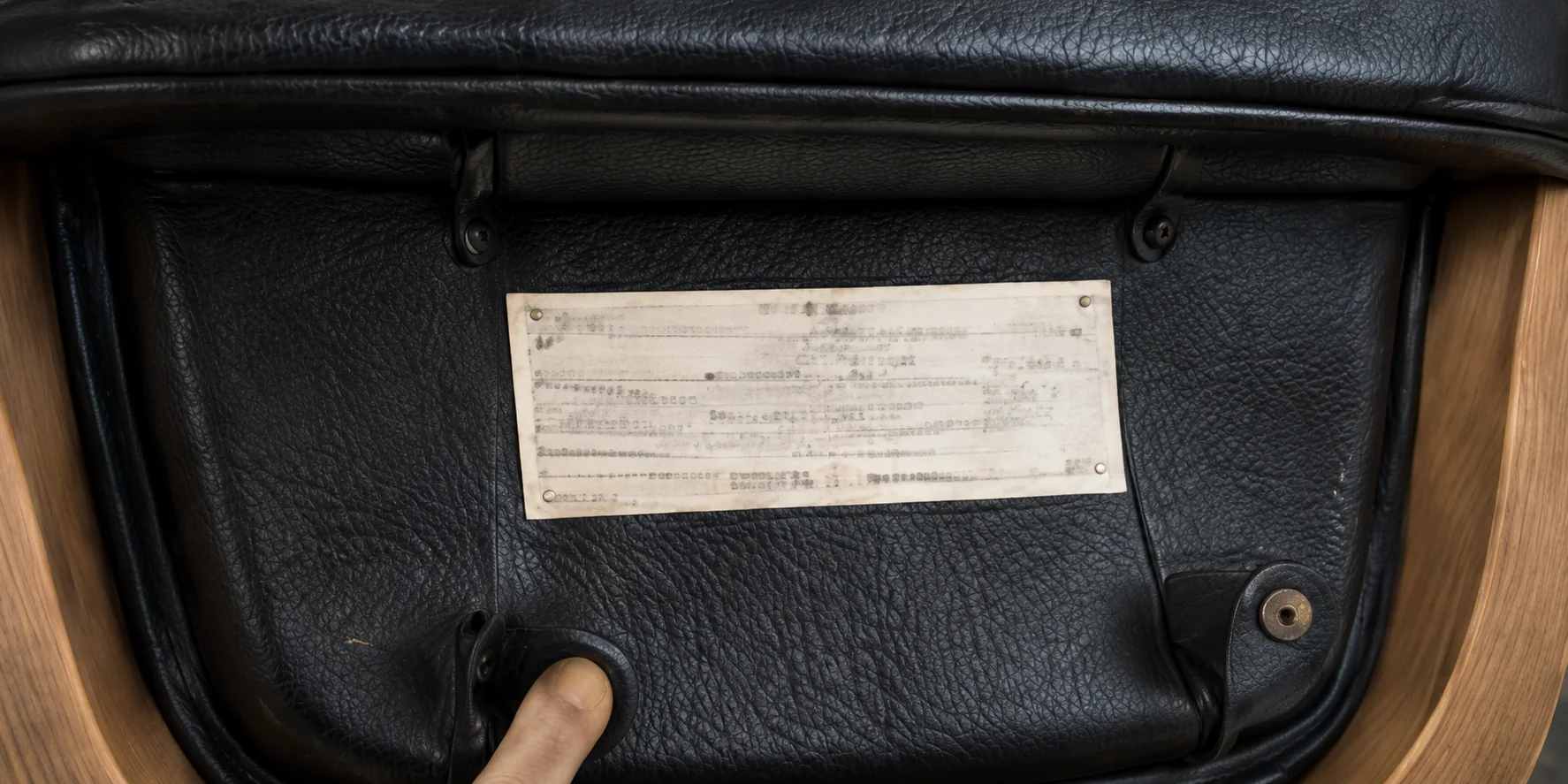 The maker's label on the underside of a black leather lounge chair shell