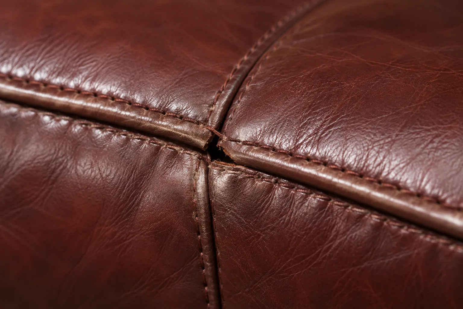 Close view of a completed seam repair on burgundy leather