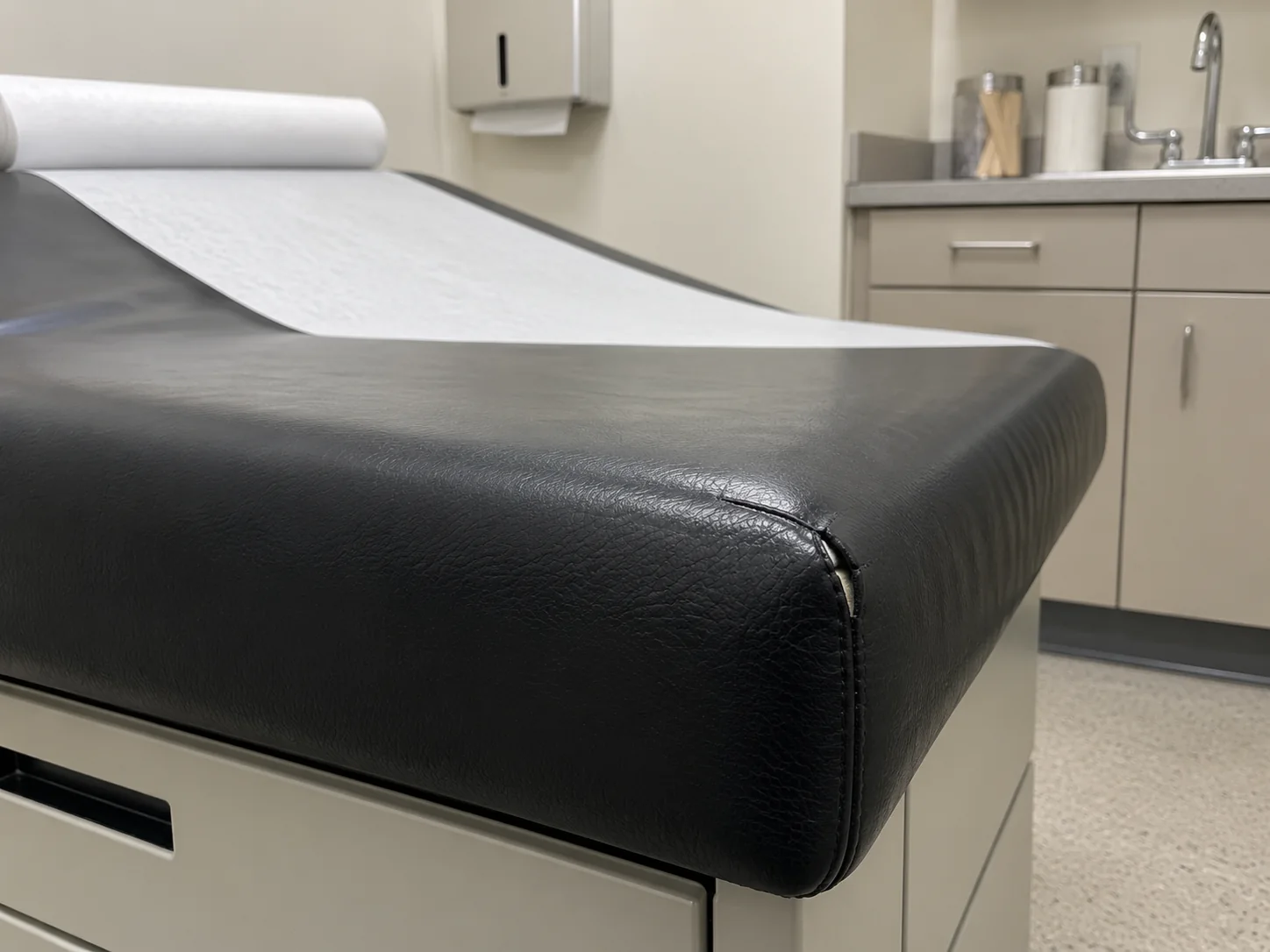 Before: a split in the black vinyl at the head end corner of an exam table