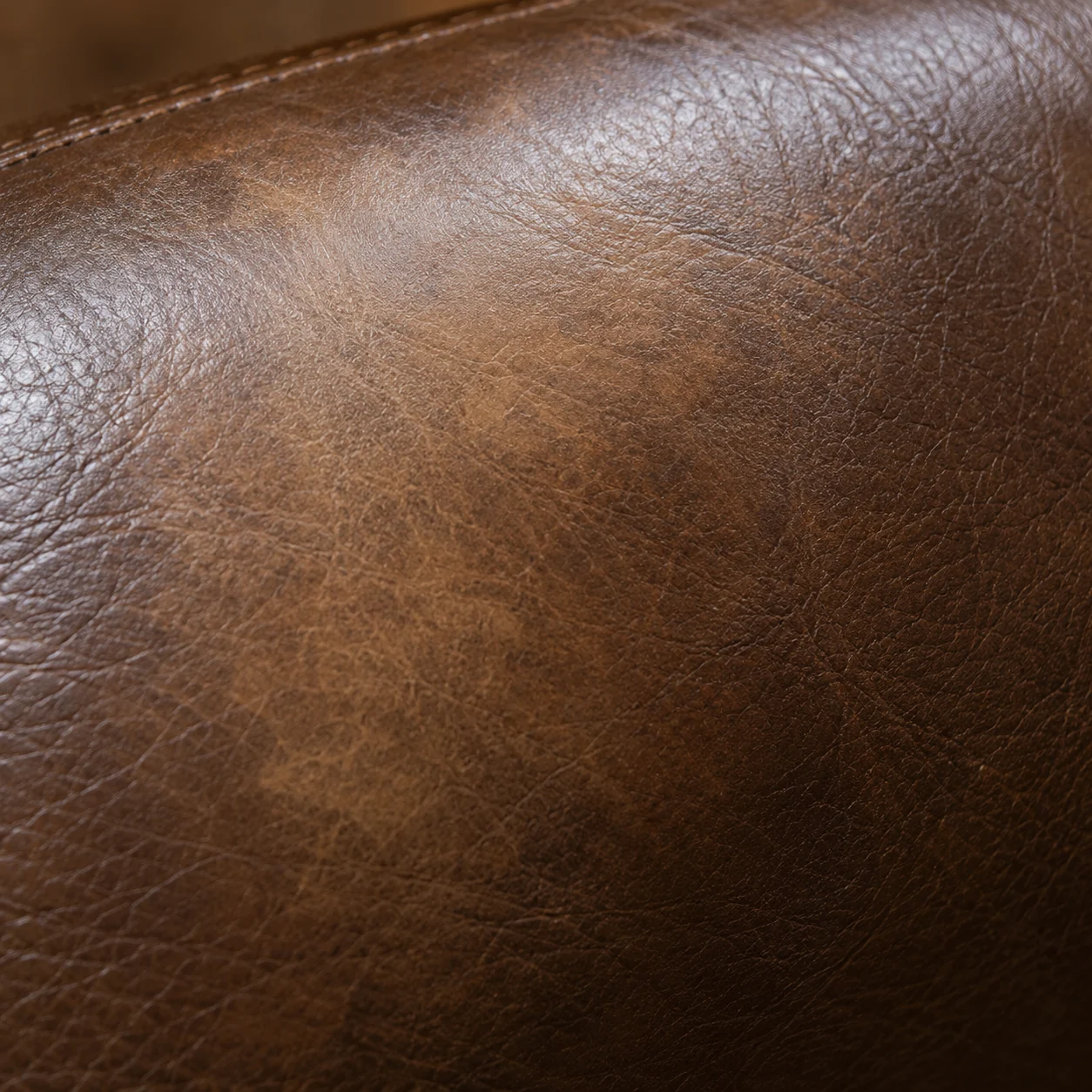 A pale faded patch on the brown leather back of a massage chair